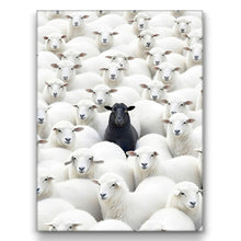 Load image into Gallery viewer, A canvas print wall art depicting a herd of white sheep with a single black sheep in the center, representing the concept of being different or standing out.